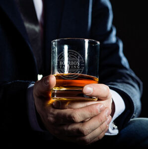 Man in blue suit holding glass of bourbon