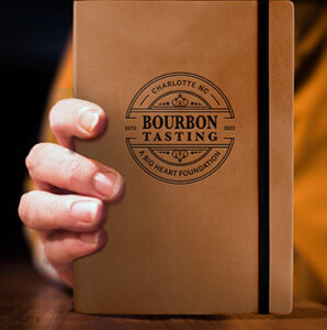 A hand holding a leather bound notebook